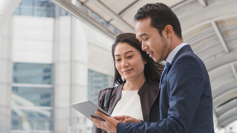 Male executive showing something to a female client on his tablet