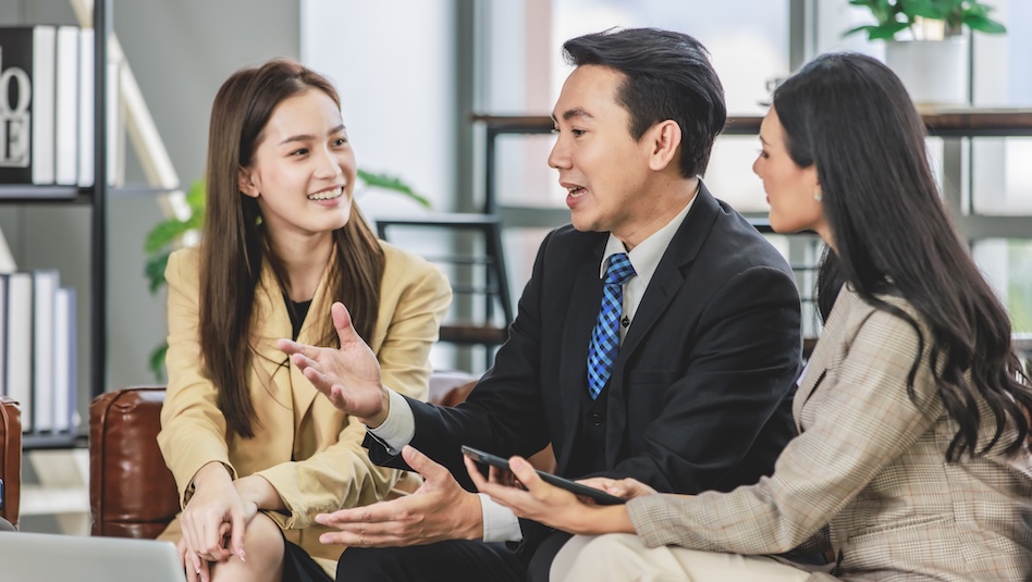 Group of millennial Asian young happy male female businessman businesswoman employee staff in formal business suit sitting on leather sofa smiling discussing brainstorming talking together in office